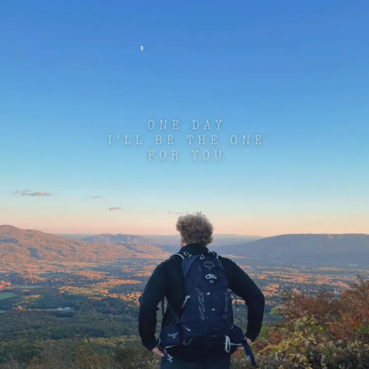 redheaded man standing on a mountain cliff 
                    overlooking a valley.